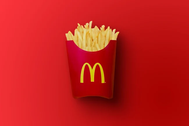 Eine Pommes-Tüte von McDonald’s auf rotem Hintergrund.