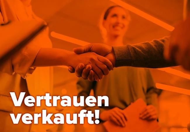 Zwei Personen geben sich die Hand, im Hintergrund steht eine weitere Person, dazu ein orangener Filter und der Schriftzug „Vertrauen verkauft!“.